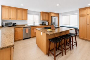 Une cuisine moderne avec des meubles en bois, un réfrigérateur en acier inoxydable, un four encastré et un plan de travail en granit.