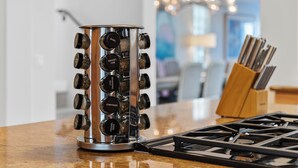 A kitchen with a stainless steel spice rack holding various spices, a gas stove, and a wooden utensil holder. - Luxury Beach Mansion - Roof Deck- Steps to Sand (Oxnard)
