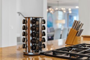 A kitchen with a stainless steel spice rack holding various spices, a gas stove, and a wooden utensil holder.