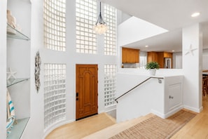 Un interior moderno con una escalera que conduce a un segundo piso, una zona de cocina y una estrella de mar decorativa en la pared.