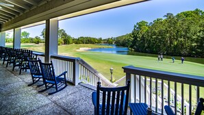 A covered outdoor seating area with chairs and a view of a golf course.