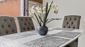 Une table à manger agrémentée d’un vase de fleurs blanches, de chaises à revêtement gris et d’un chemin de table décoratif.