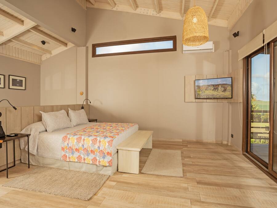 A bedroom with a bed, bedside table, lamp, and a large window.