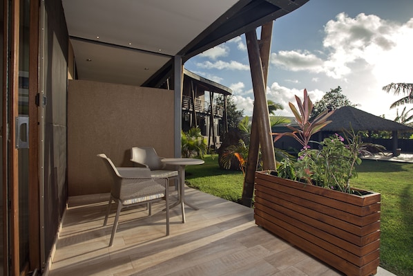 Un patio exterior moderno con zona de estar, una jardinera de madera y vistas a una casa y jardín.