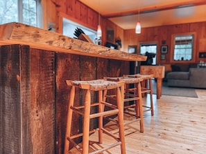 A wooden bar with three stools in a rustic interior.