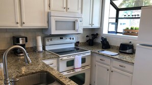 A kitchen with white cabinets, a stainless steel sink, a microwave, an oven, and a toaster. - Newly renovated lakefront townhome with incredible views of Mille Lacs Lake (Onamia)