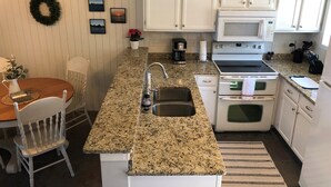 A kitchen with white cabinets, a granite countertop, a microwave, a stove, and a sink. - Newly renovated lakefront townhome with incredible views of Mille Lacs Lake (Onamia)