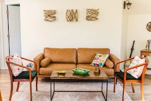 Relax in this inviting living room with a leather sofa, coffee table, and comfortable chairs.