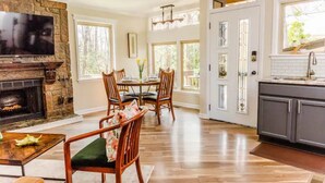 A spacious kitchen with a stone fireplace, wooden dining table, and chairs. - The Owl House cheerful, bright, updated 2B A-frame (Hot Springs)