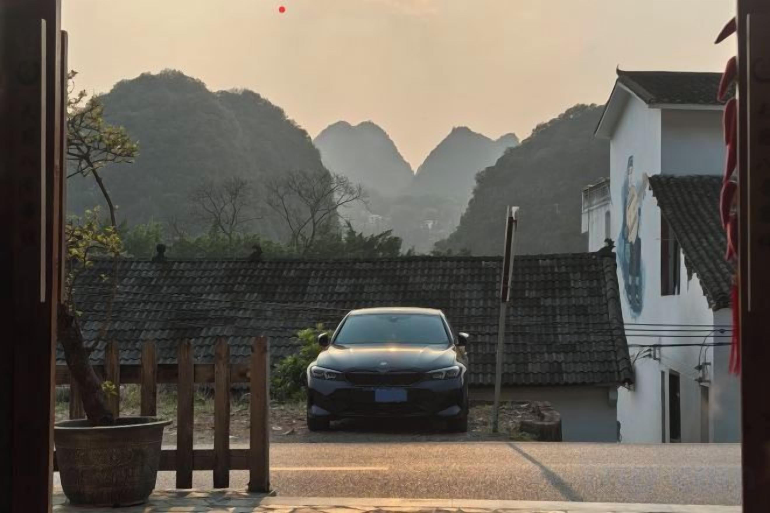 A car parked in front of a traditional building with a tiled roof and a mountainous backdrop.