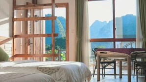 A bedroom with a bed, a wooden ladder, a table with chairs, and a large window with a mountain view. - Tianla Bayin Inn (Xingyi)