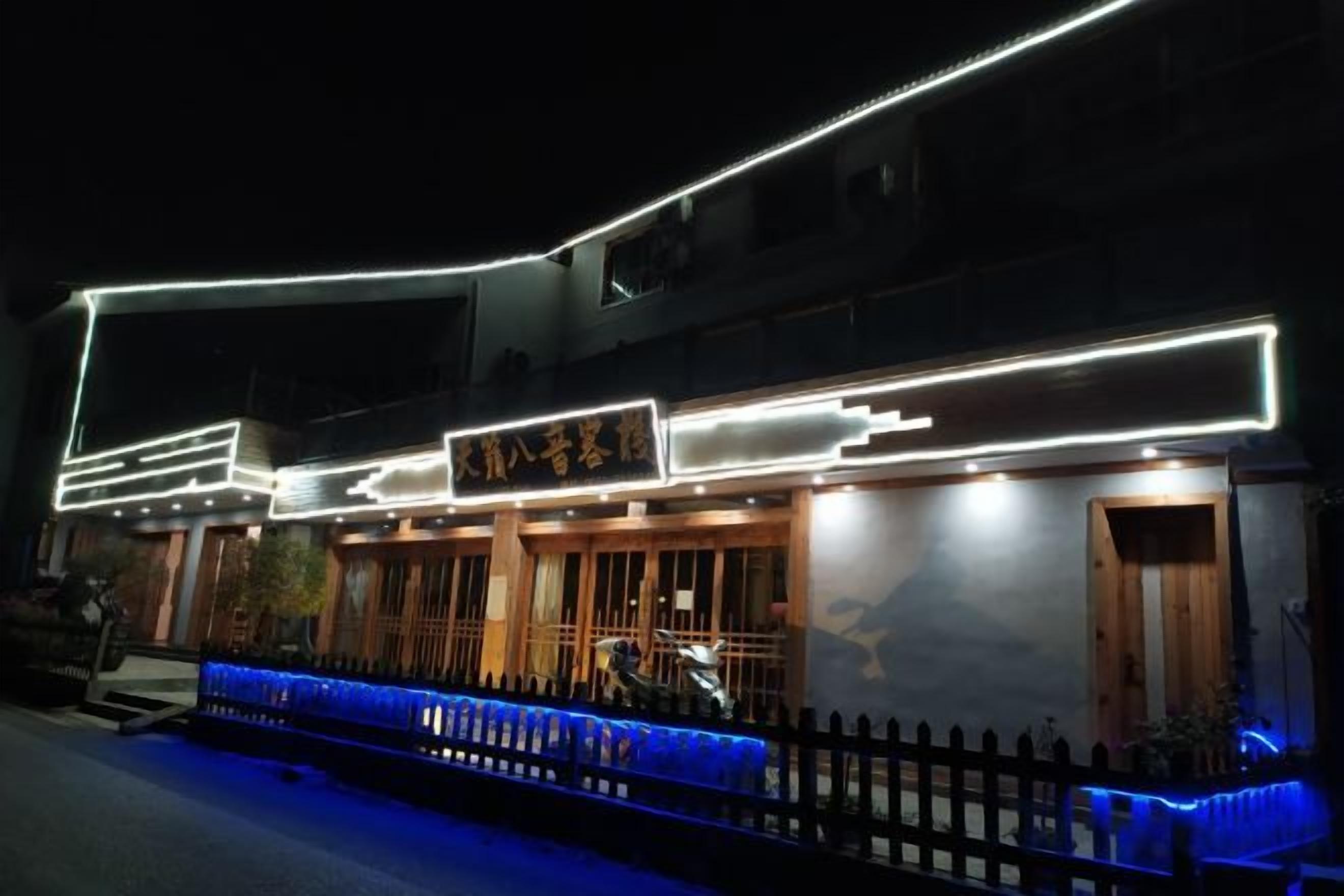 Um edifício com sinalização iluminada e um caminho com iluminação azul que leva à entrada.