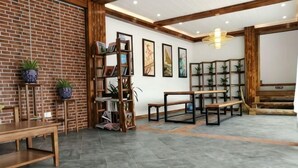 A spacious room with a brick wall, a wooden bookshelf, a dining table, and a piano. - Tianla Bayin Inn (Xingyi)