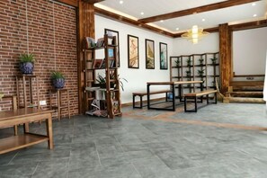 Una habitación amplia con pared de ladrillo, una estantería de madera, una mesa de comedor y un piano.