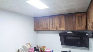 A kitchen with wooden cabinets, a microwave, and various kitchen items on the counter.