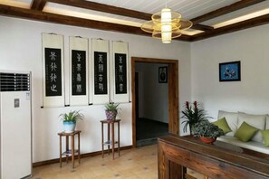 Une pièce de style japonais traditionnel, avec un sol recouvert de tatamis, une table en bois, un canapé avec des coussins et un luminaire suspendu.