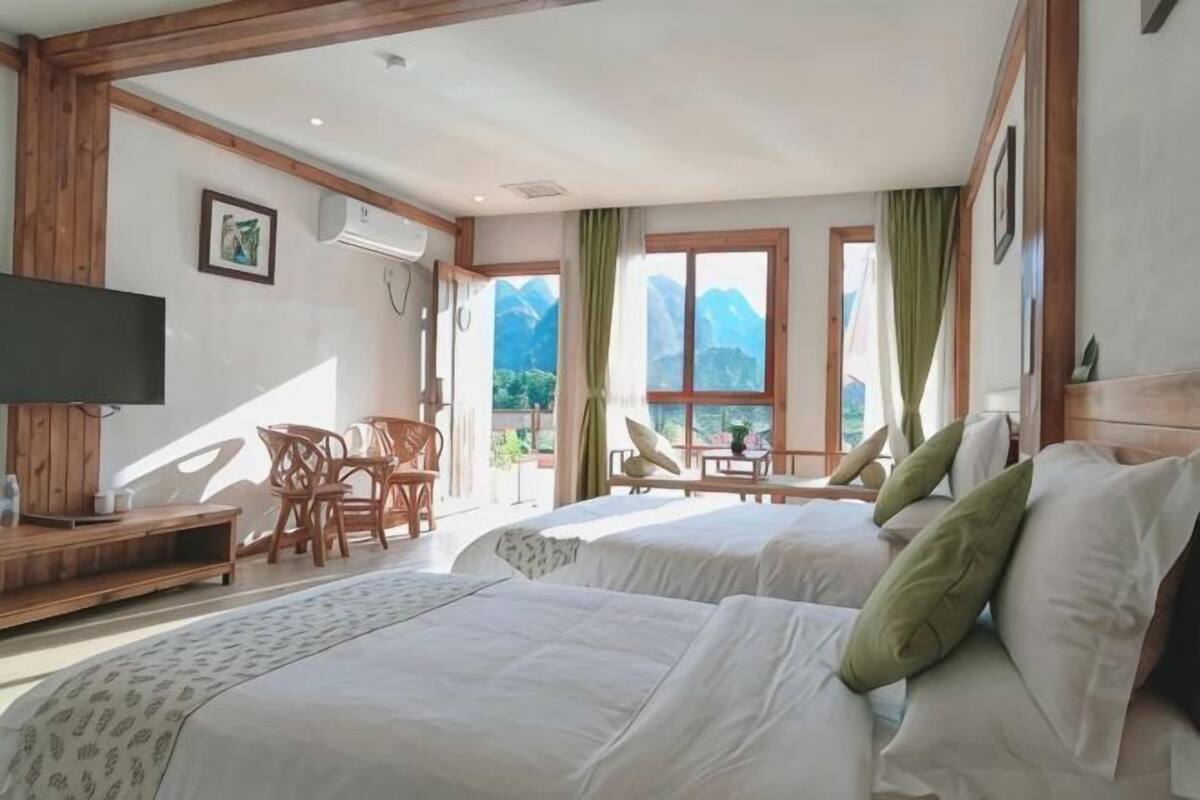 Une chambre d’hôtel avec deux lits, une télévision, un bureau et une vue sur les montagnes.