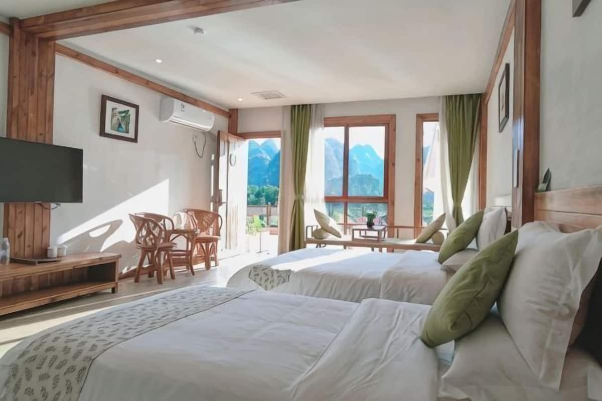 Une chambre dâhĂŽtel avec deux lits, une tĂ©lĂ©vision, un bureau et une vue sur les montagnes.