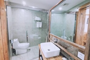 Een moderne badkamer met een douchecabine van glas, een wit toilet en een houten wastafelmeubel met een wastafel.