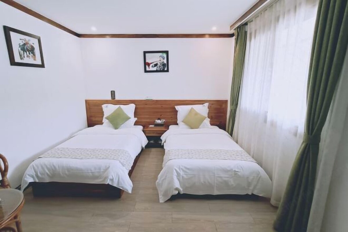 Een hotelkamer met twee enkele bedden, een houten hoofdbord, een tafeltje en een stoel.