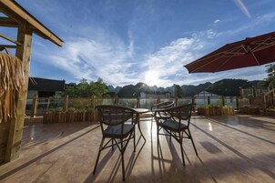 Un patio al aire libre con una mesa y sillas, una pérgola de madera y vistas a montañas.