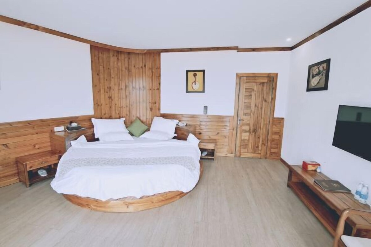 Een slaapkamer met een rond bed, een houten hoofdeinde, een televisie en een bankje.