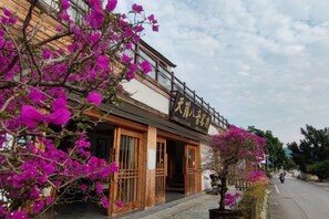 A traditional building with a sign, wooden doors, and a street view.