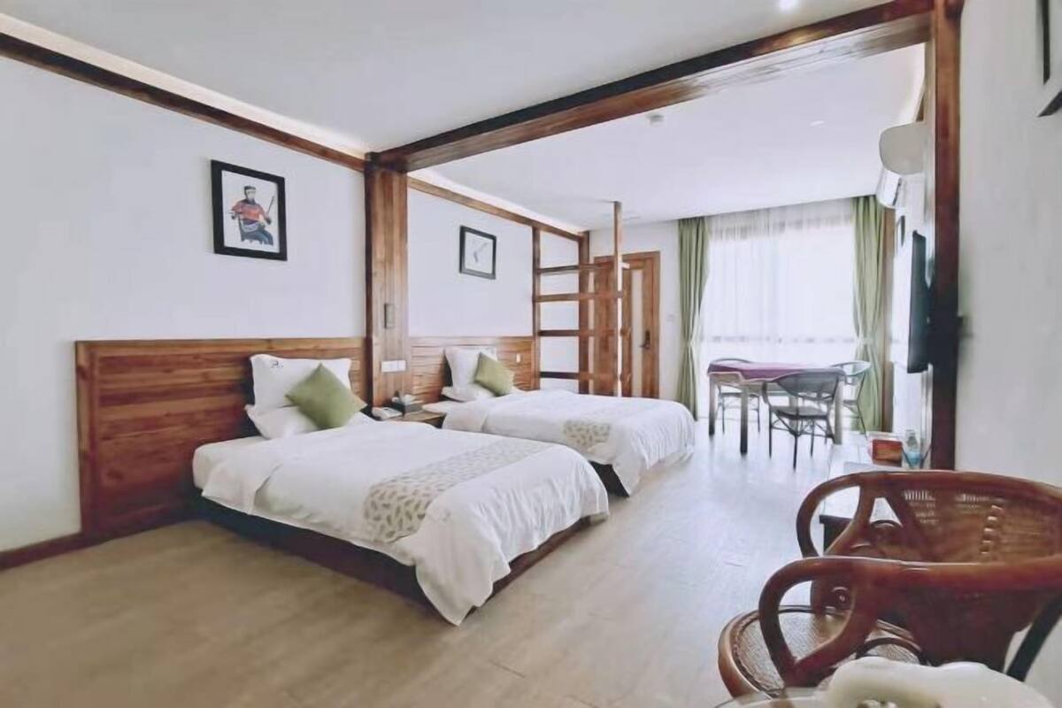 Une chambre d’hôtel avec deux lits, des têtes de lit en bois, une petite table et une chaise.