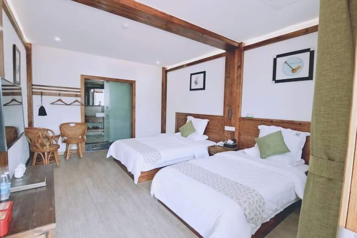 Une chambre d’hôtel avec deux lits, des têtes de lit en bois, un bureau avec des chaises et un miroir.