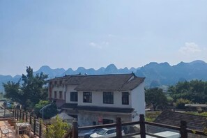 Ein Wohngebäude mit traditionellem Design, einem Balkon und Blick auf ferne Berge.