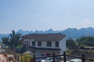 A residential building with a traditional design, a balcony, and a view of distant mountains.