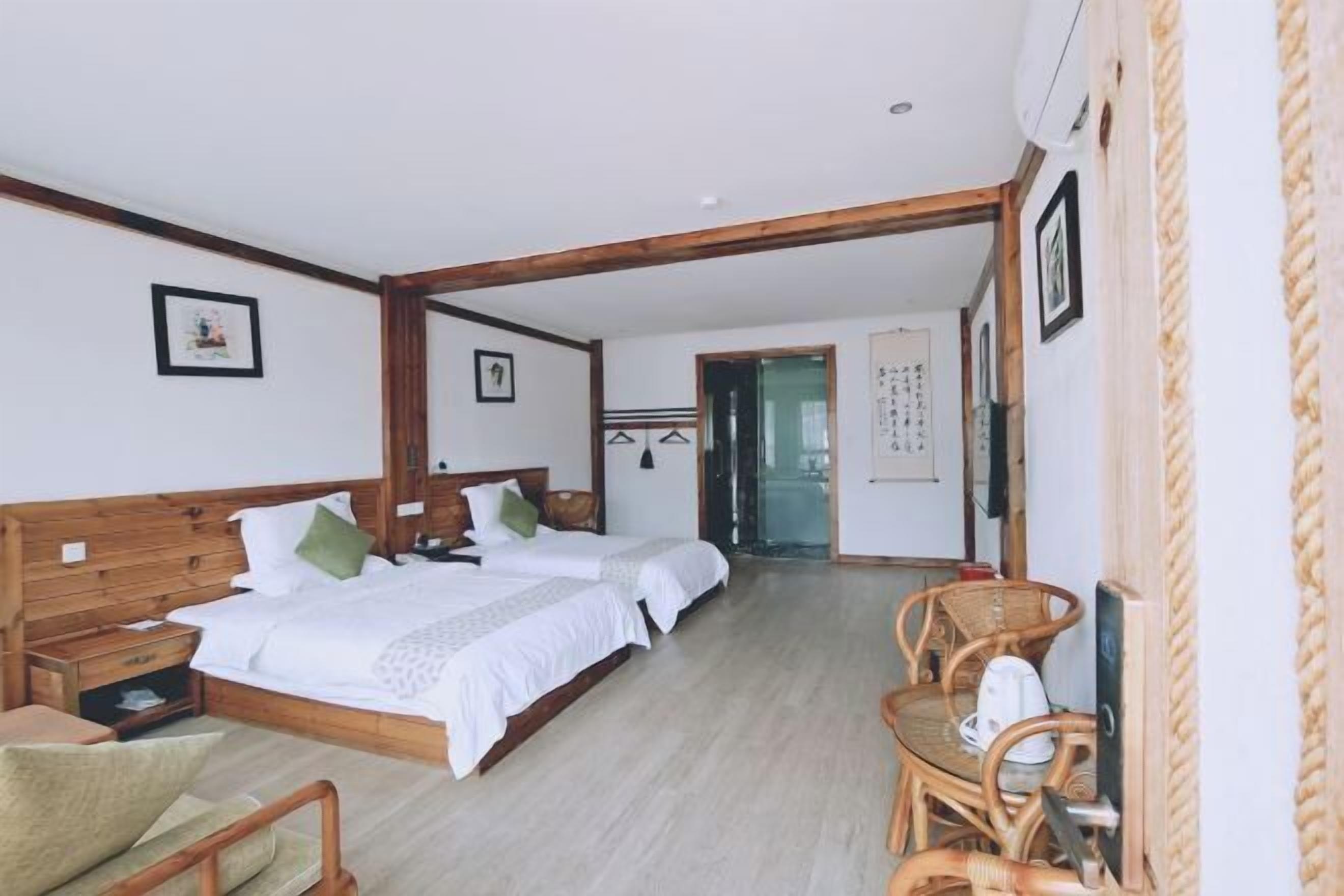 A bedroom with a wooden bed, a bedside table, a chair, and a small table with a kettle.