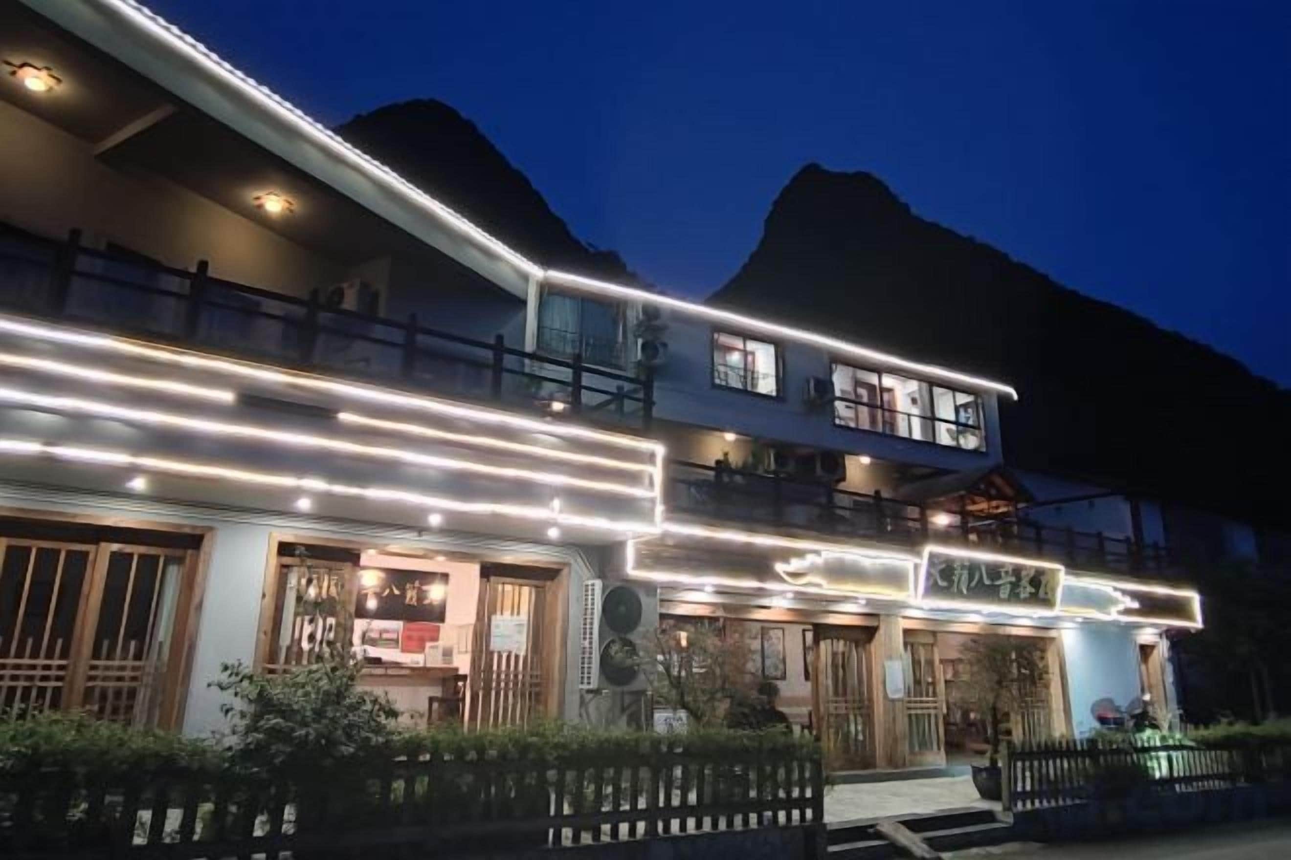 Un edificio de dos pisos con señalización iluminada y un balcón.