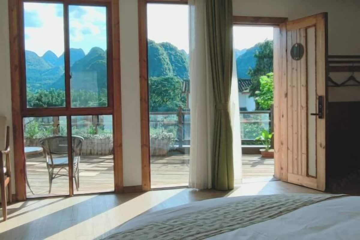 Une chambre avec une grande fenêtre, une porte en bois et une vue sur les montagnes.