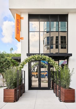 An outdoor seating area with wicker furniture, a bar, and lush greenery. at Arlo Wynwood Miami