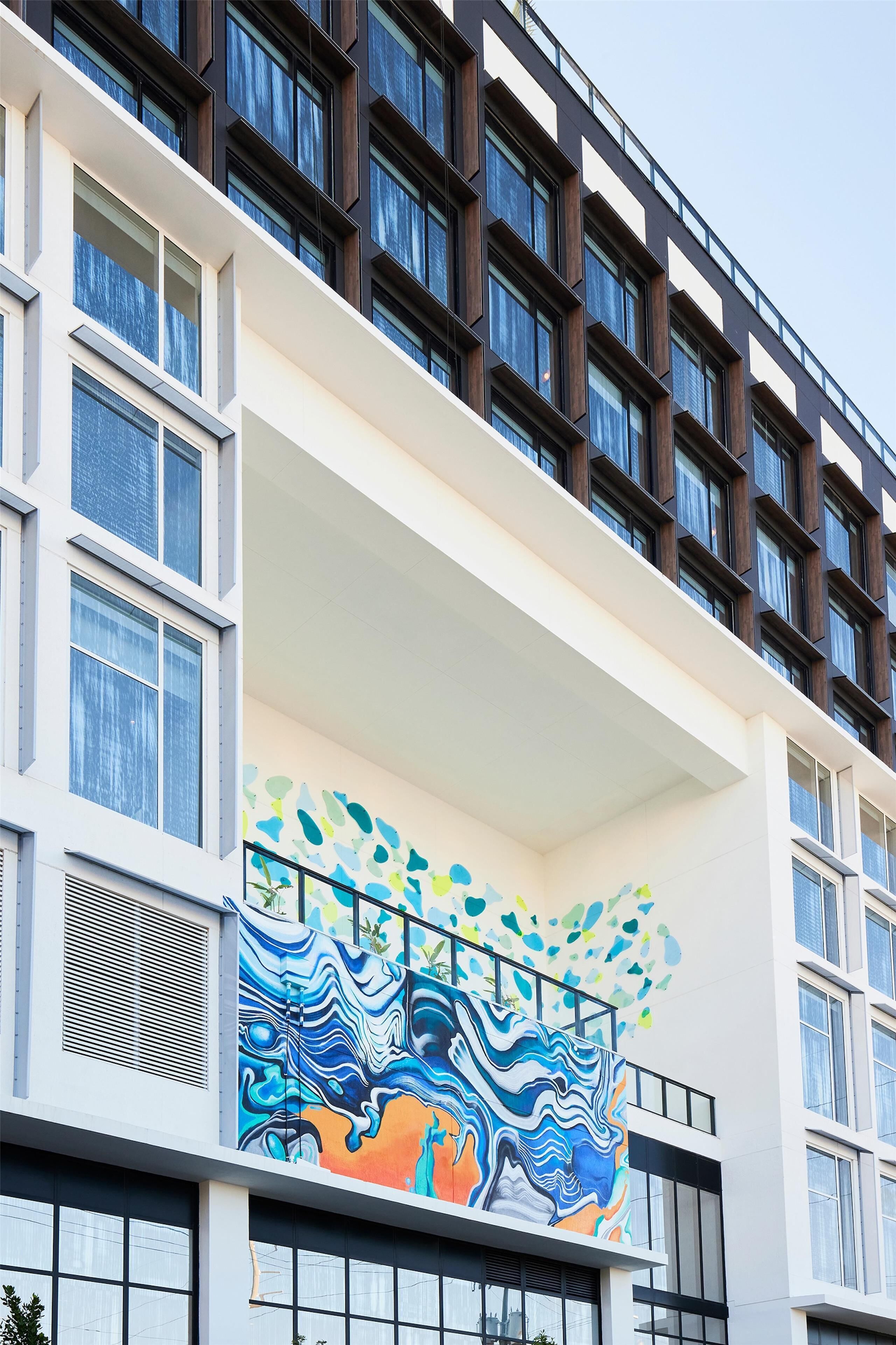 A modern building with a balcony featuring a colorful abstract mural.