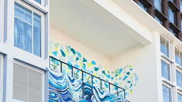 A modern building with a balcony featuring a colorful abstract mural.