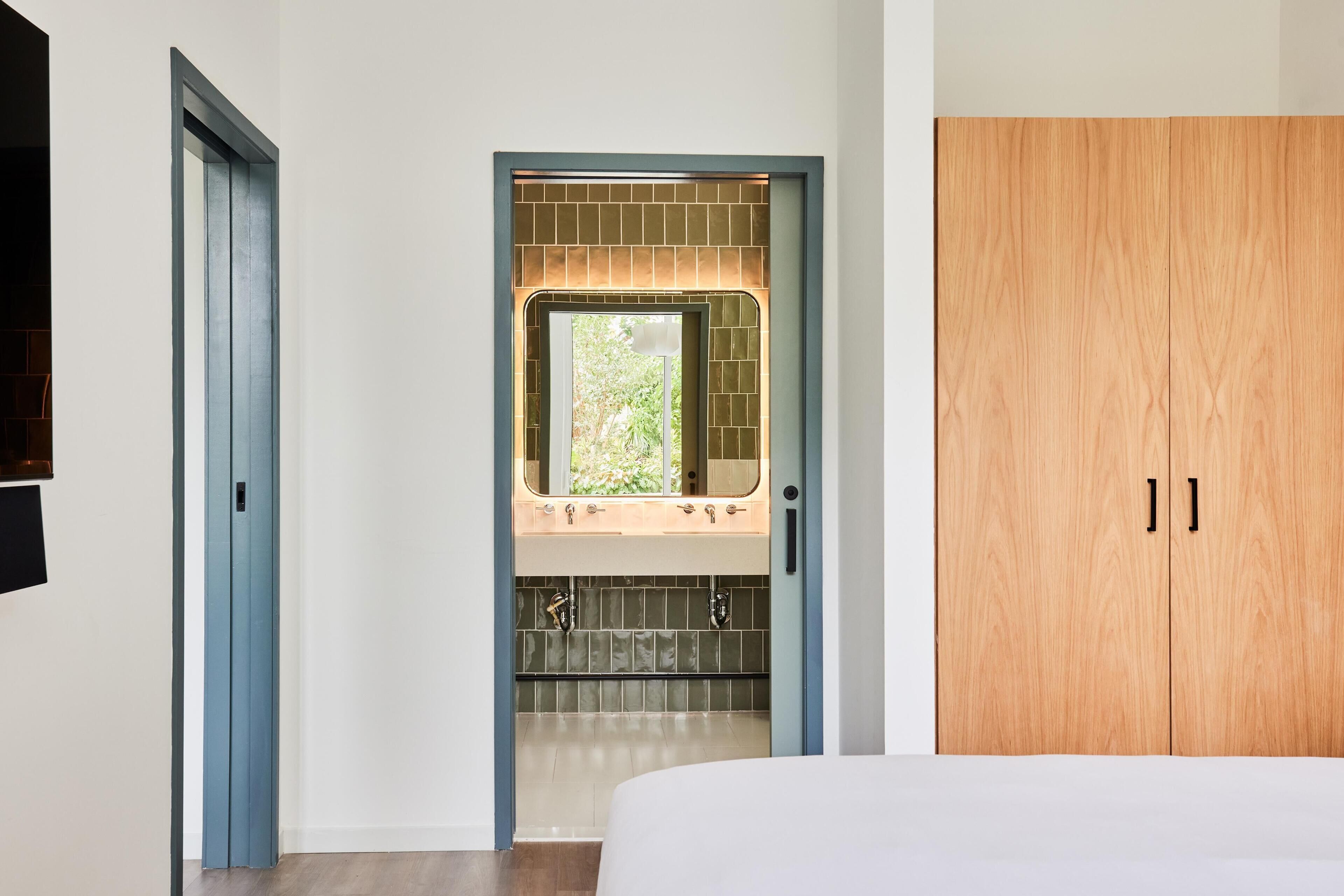 Una camera da letto con un letto, un armadio in legno e un bagno con lavandino e specchio.