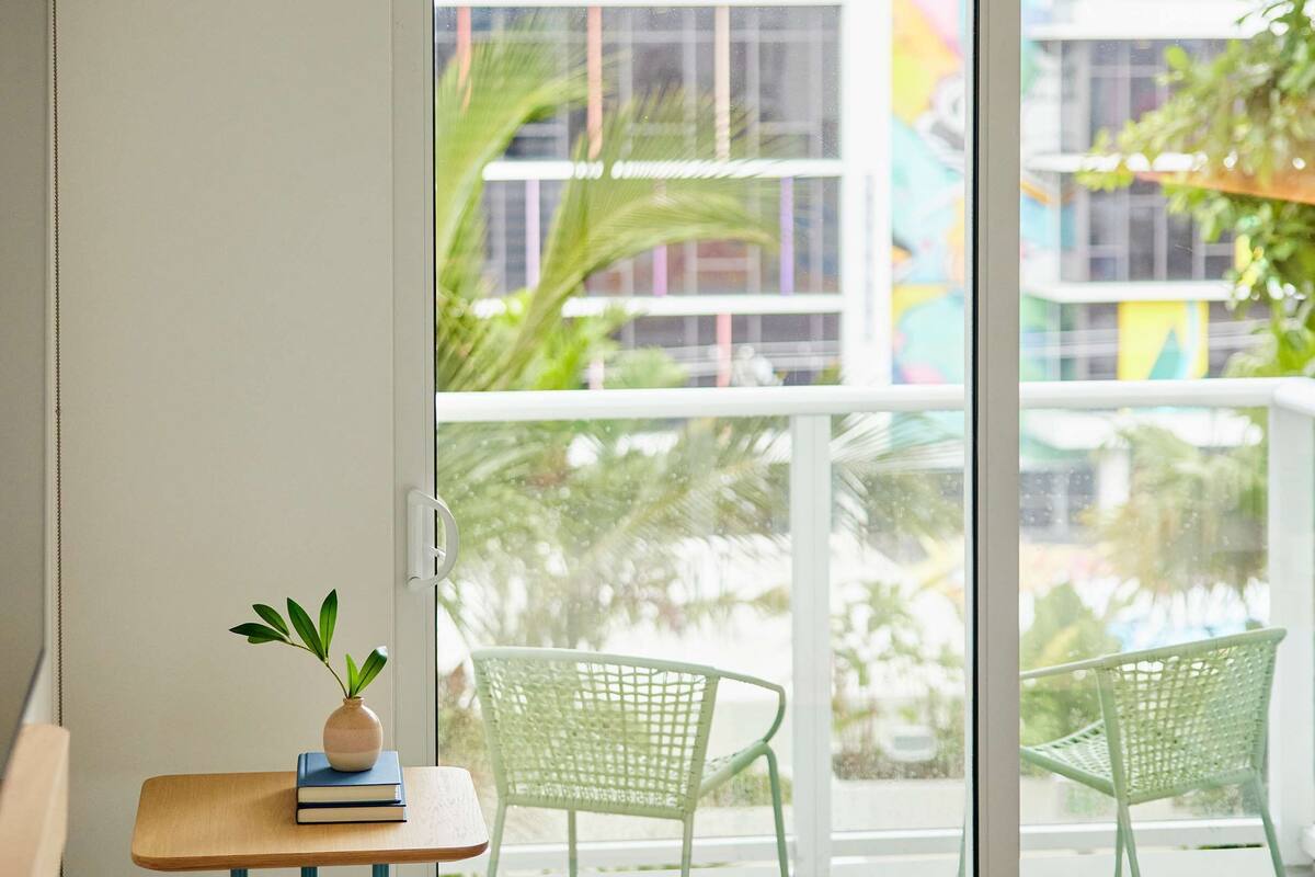 A hotel room with a balcony, a small table with a plant, and two chairs.