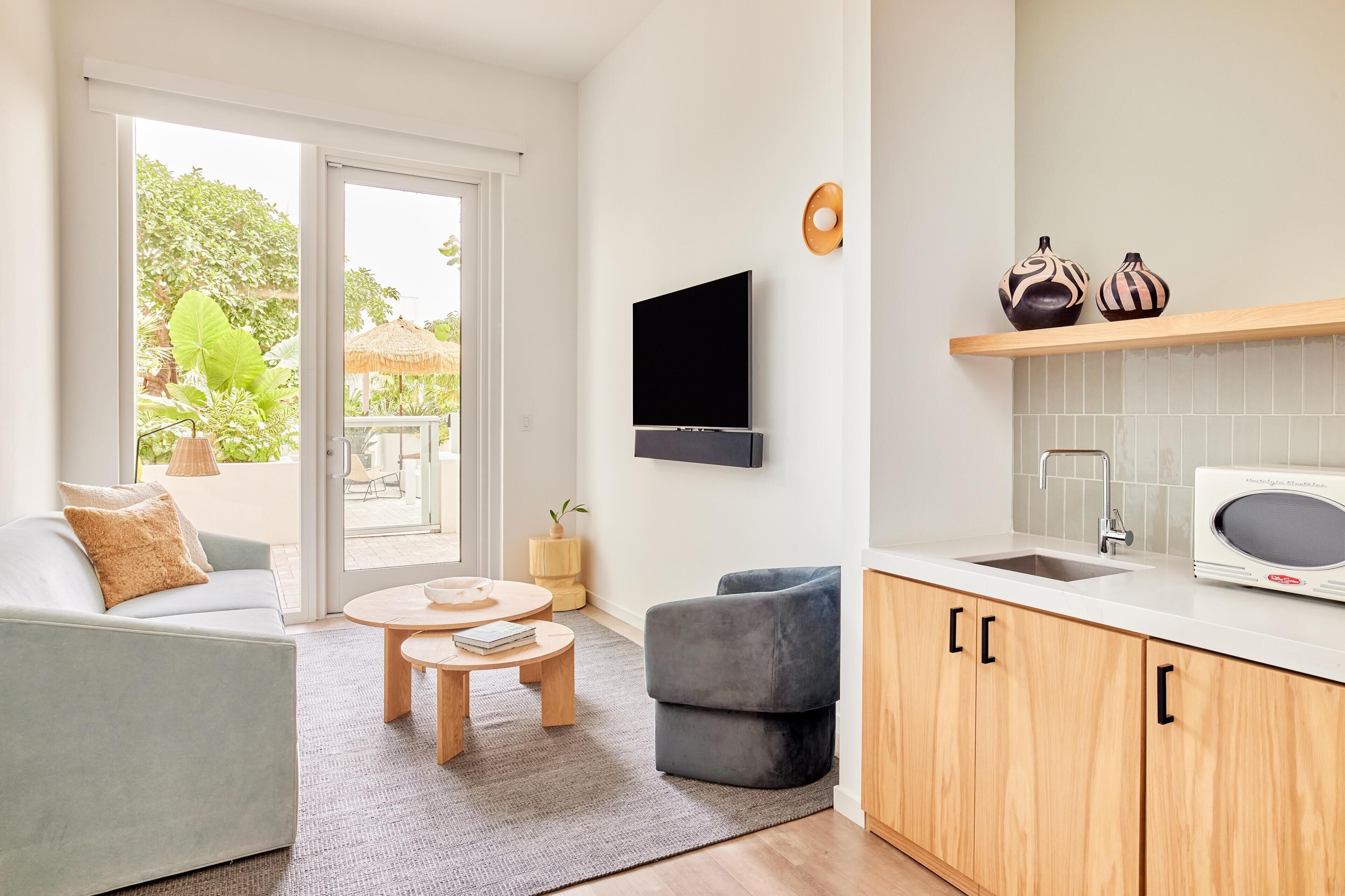 Ein modernes Wohnzimmer mit einer Couch, einem Couchtisch und einem an der Wand montierten Fernseher.