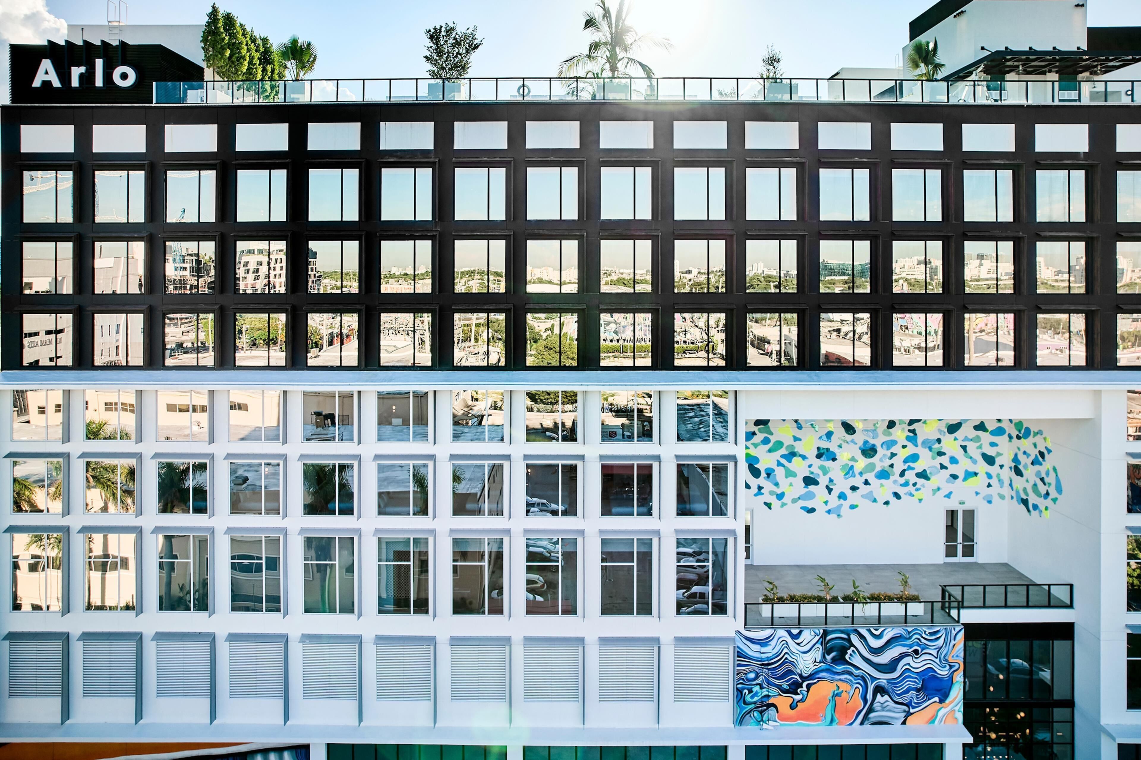 Un edificio moderno con una fachada de ventanas en forma de cuadrícula y un letrero que dice 'Arlo'.
