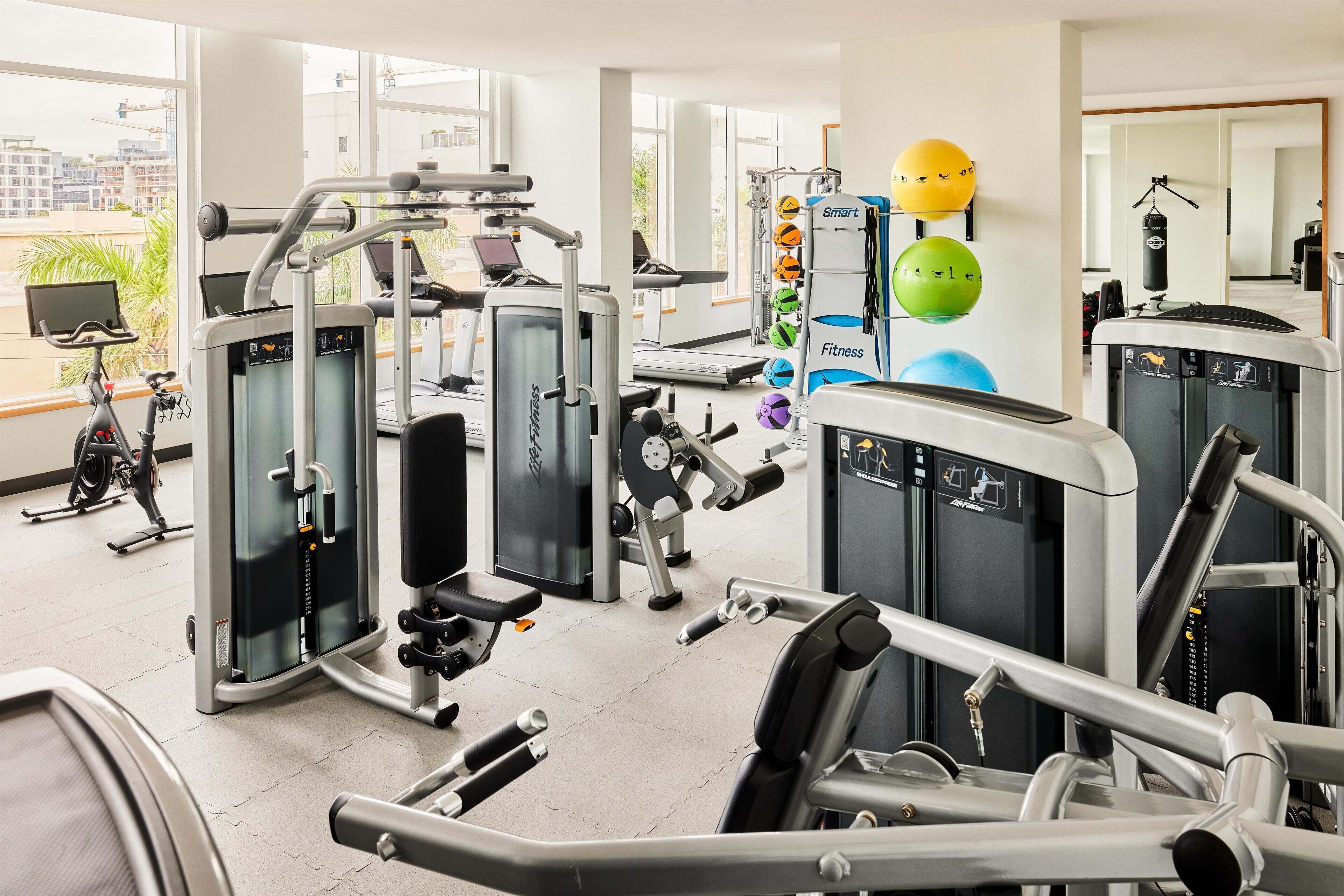 A gym with various exercise equipment, including treadmills, weight machines, and exercise balls.