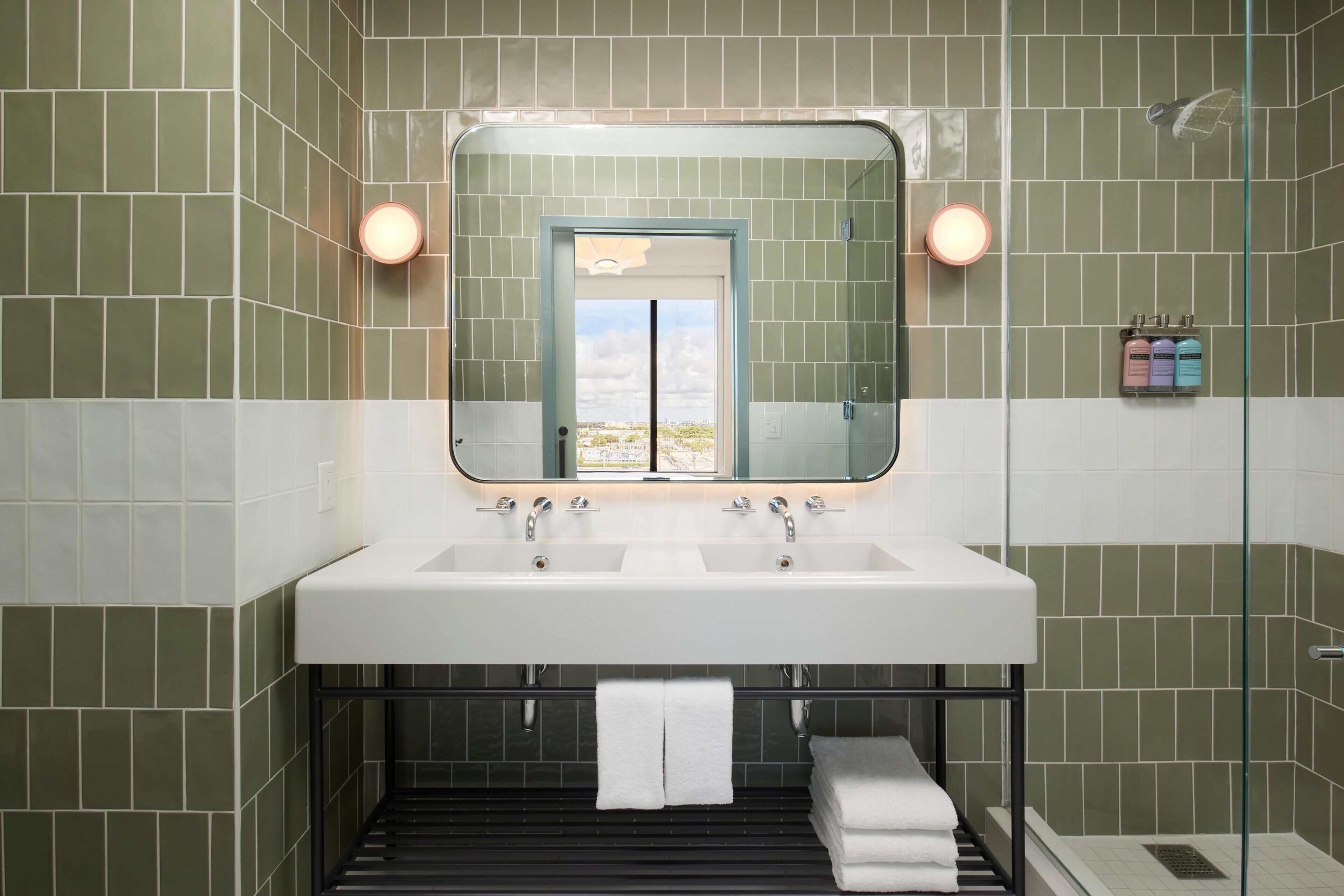A bathroom with two sinks, a large mirror, and a glass shower enclosure.
