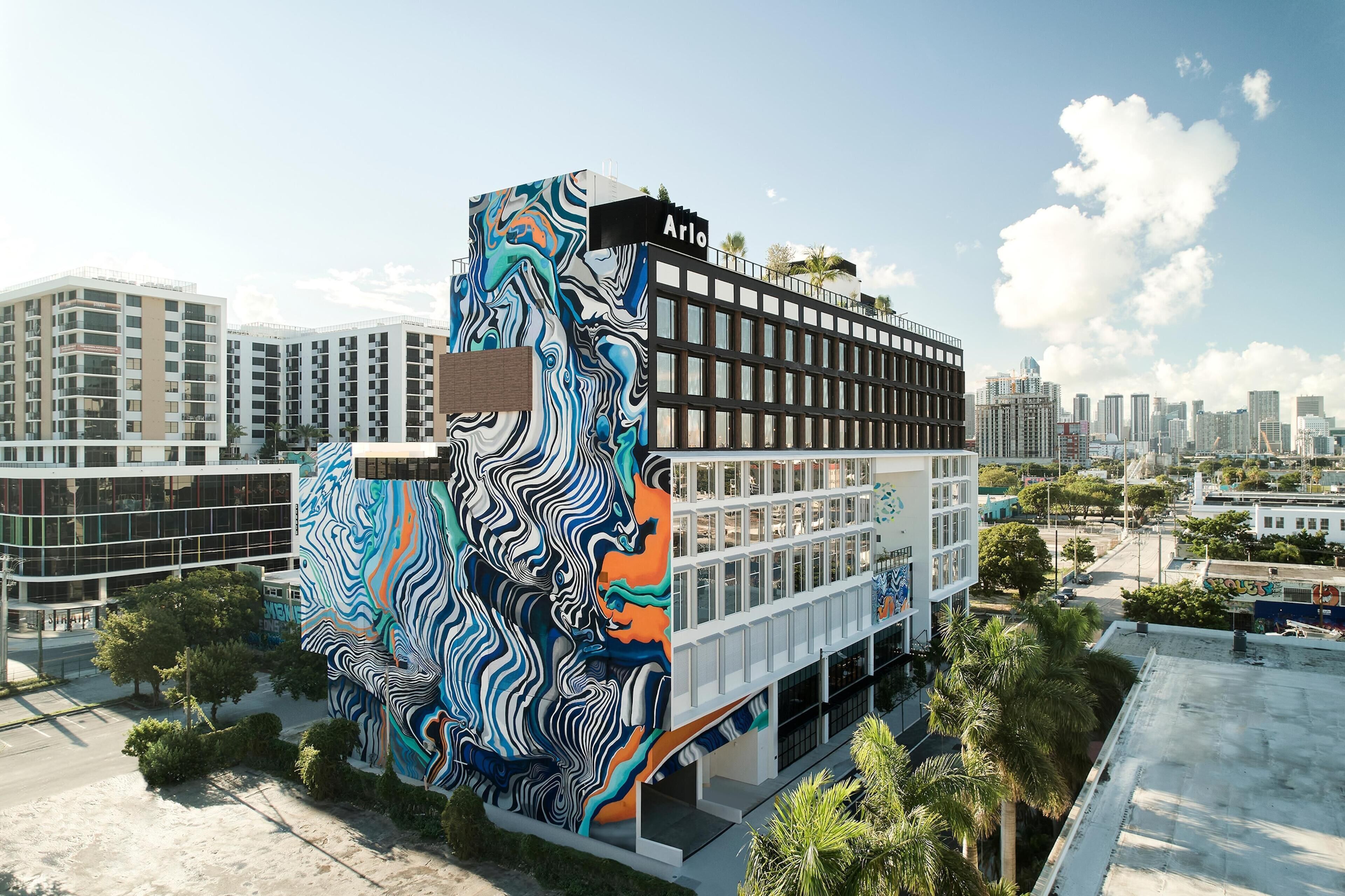 A modern building with a unique mural on its facade, featuring a mix of geometric and organic shapes.