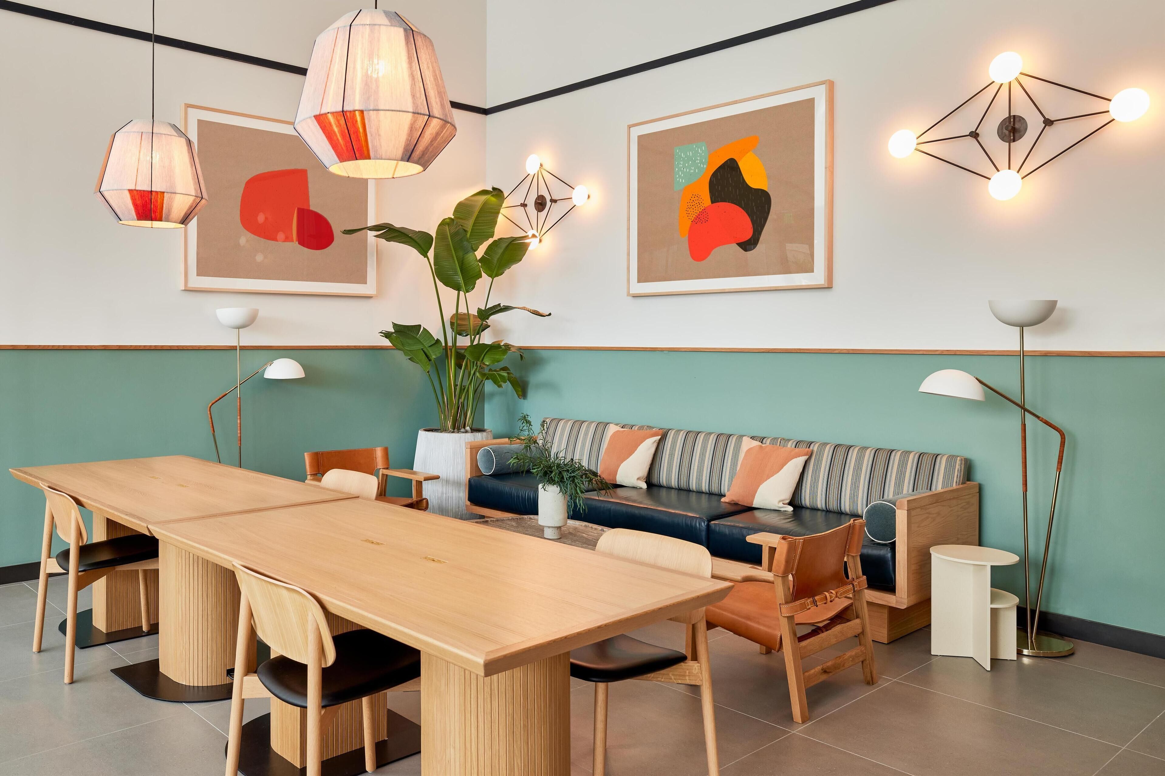 Een moderne woonkamer met een houten eettafel, een gestreepte bank en twee hanglampen.