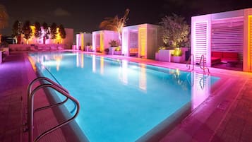 Una piscina al aire libre, camas de piscina con cargo, sombrillas