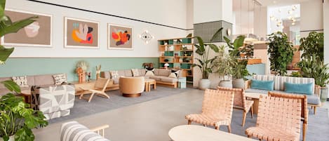 Un hall d’entrée spacieux avec un canapé, des fauteuils, une table basse et une bibliothèque.