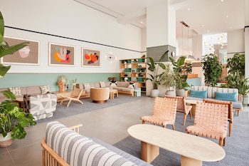 A reception desk with a light blue counter, a wooden reception area, and a modern hanging light fixture. at Arlo Wynwood Miami