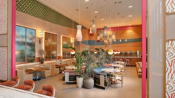 Un restaurante moderno con varias zonas de estar, incluyendo cabinas y mesas, y una cocina a la vista.