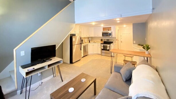 A compact living space with a kitchenette, a dining area, and a seating area with a sofa and coffee table. - Cozy Condo in the Heart of Smugglers' Notch Resort (Cambridge)